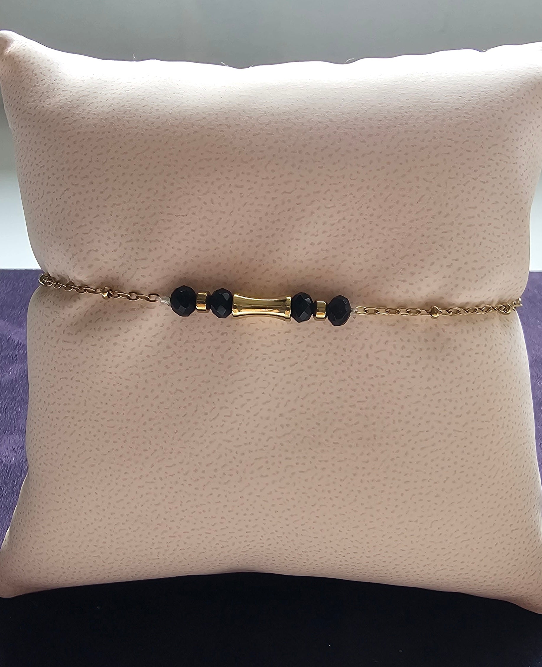 Bracelet fin chaîne dorée avec tube cylindrique doré central et cristaux noirs facettés rondelles