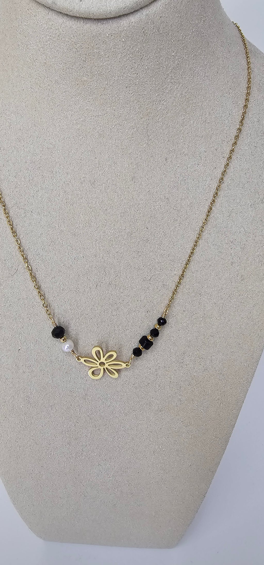 Collier fleur dorée évidée avec cristaux noirs et perle blanche sur chaîne fine dorée
