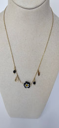 Collier charms fleur noire dorée sur présentoir
