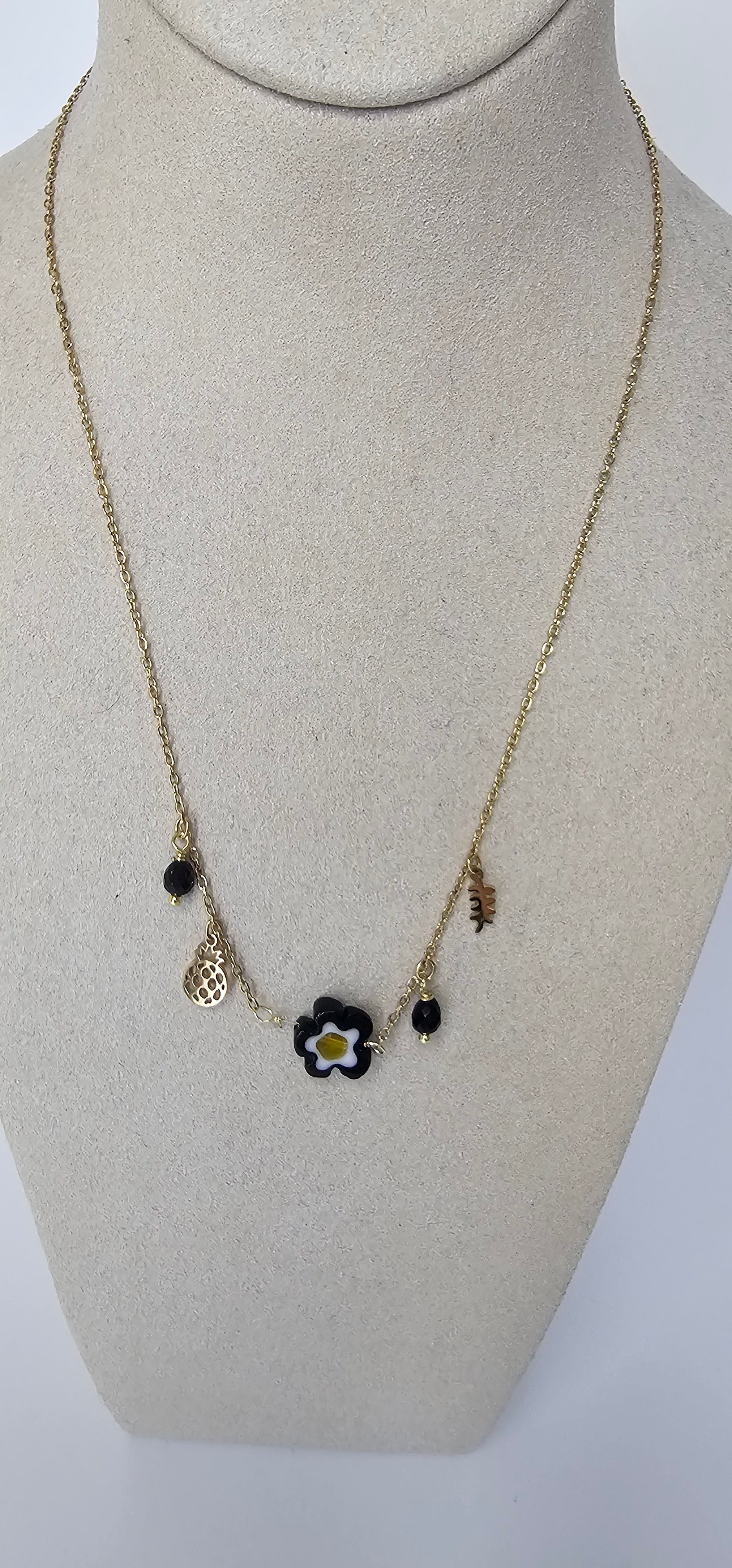 Collier charms fleur noire dorée sur présentoir