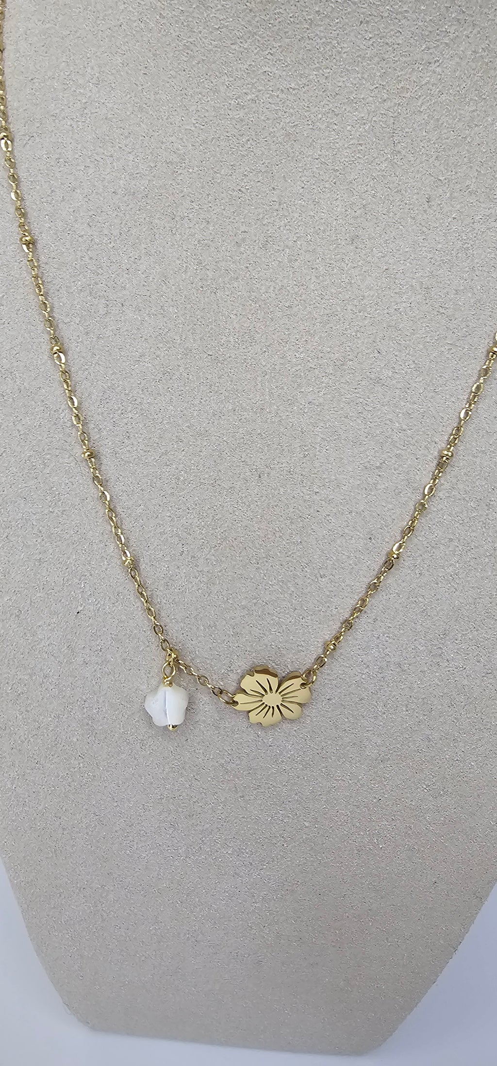 Collier fleur dorée et perle blanche sur présentoir